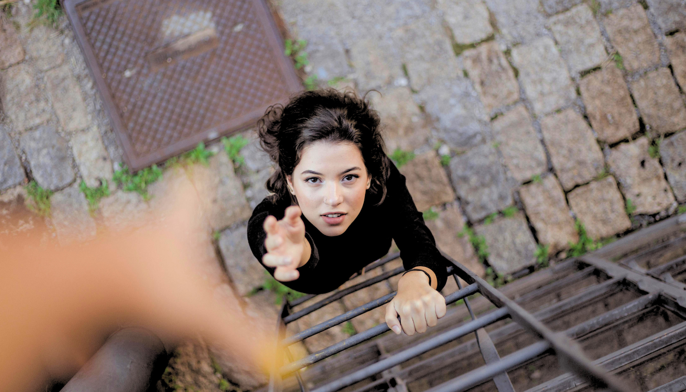 Woman reaching upwards asking for help