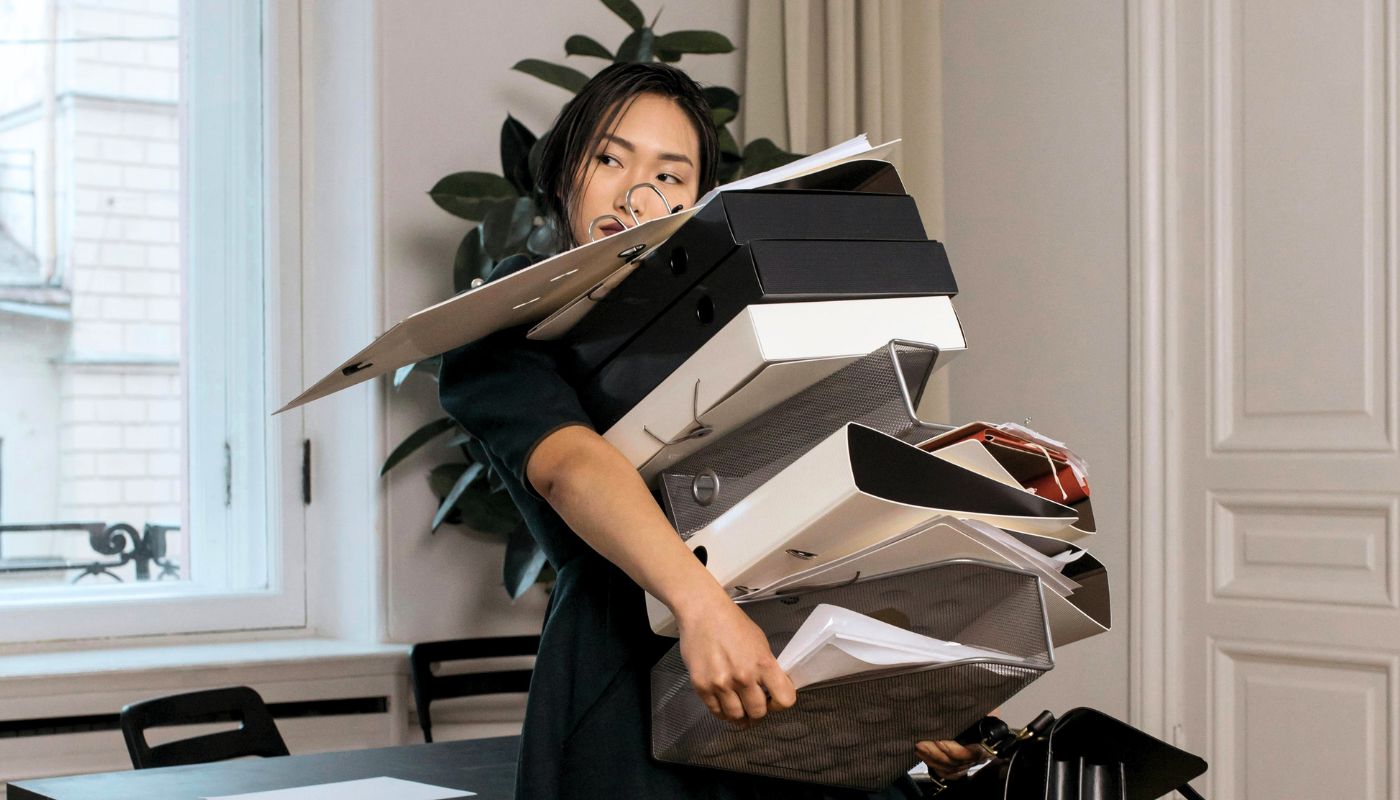 Woman holding too many boxes and folders